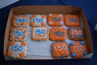 A box of decorated sugar cookies. The number 150 has been written on each cookie.