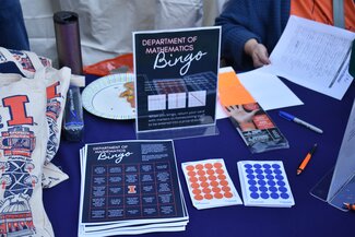 Bingo cards are stacked on a table next to University of Illinois merchandise items.