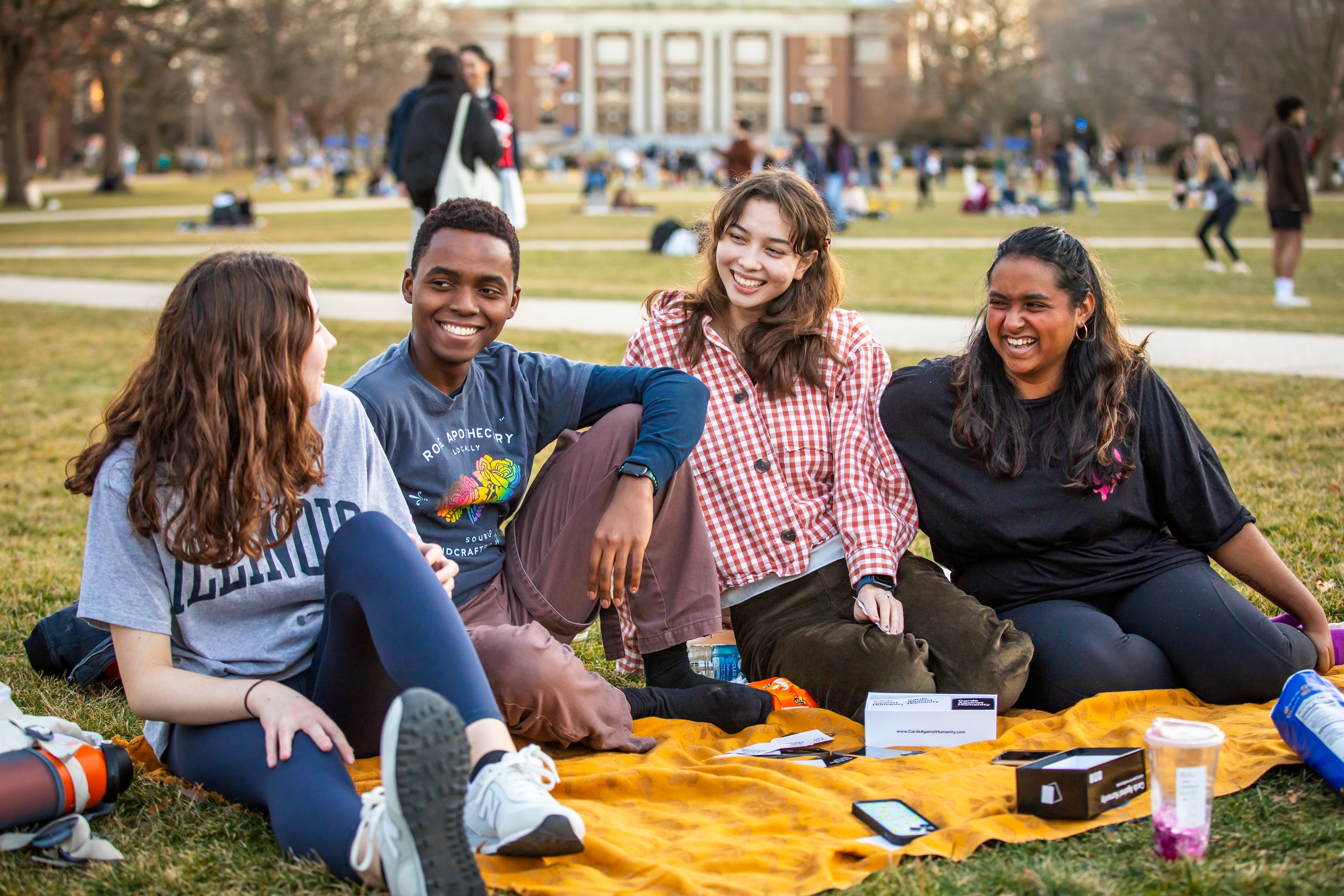 Students sitting outside on a blanket.