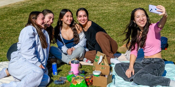 Group of women sitting on campus green.