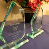 Glass awards sit atop a decorated table. The one furthest left reads "Emily Lange 2023–2024 LAS Staff Award."