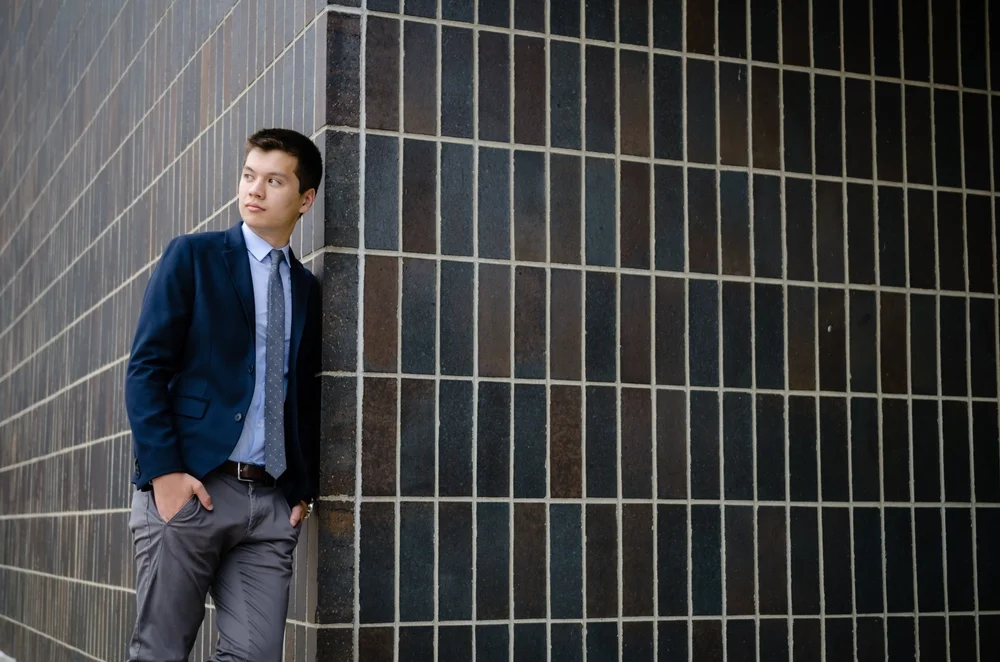 Reed Oei stands near a black tiled wall.