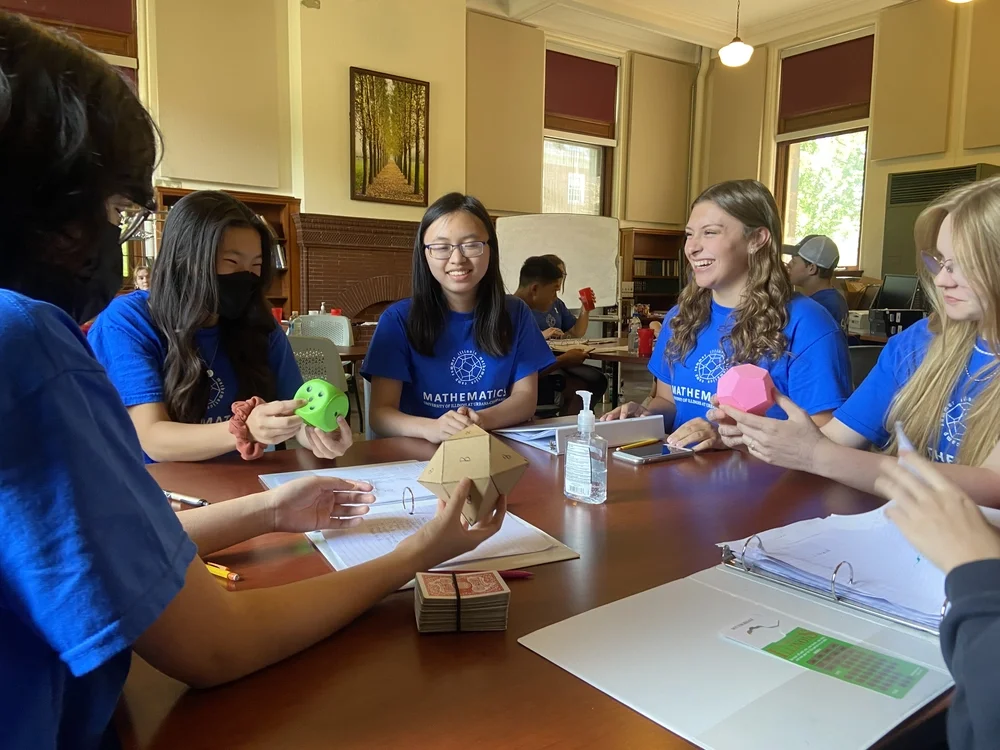 Students sitting around a table are creating mathematical models with cardboard.
