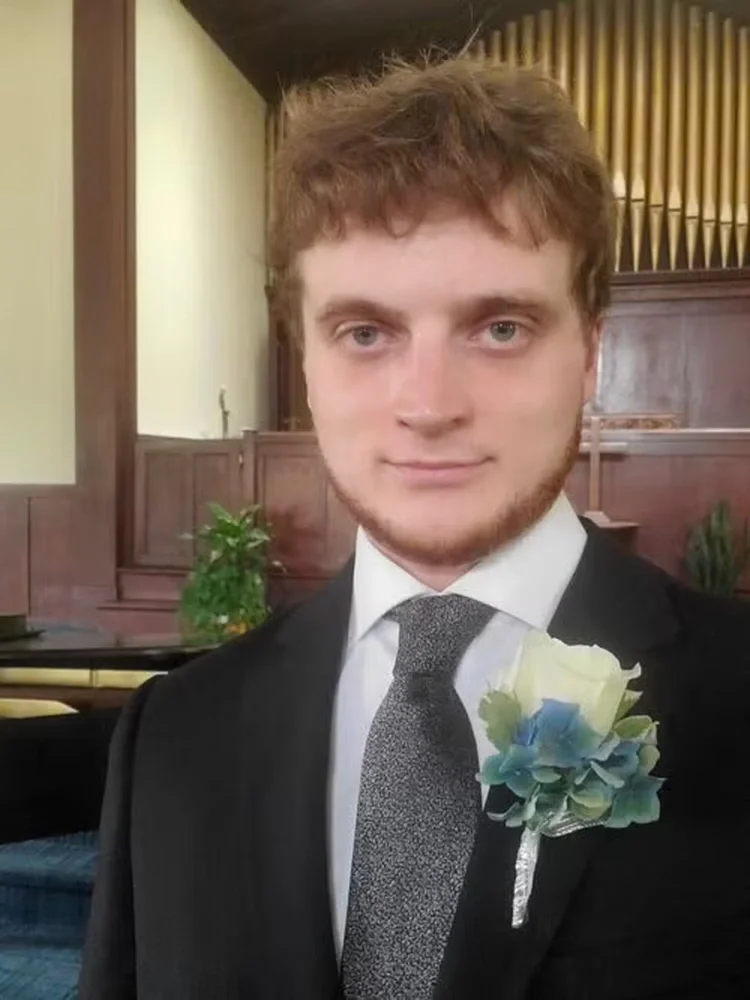 Professor Ben Castle in suit and tie with a corsage.