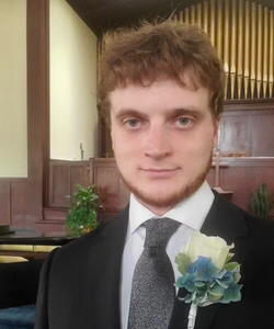 Professor Ben Castle in suit and tie with a corsage.